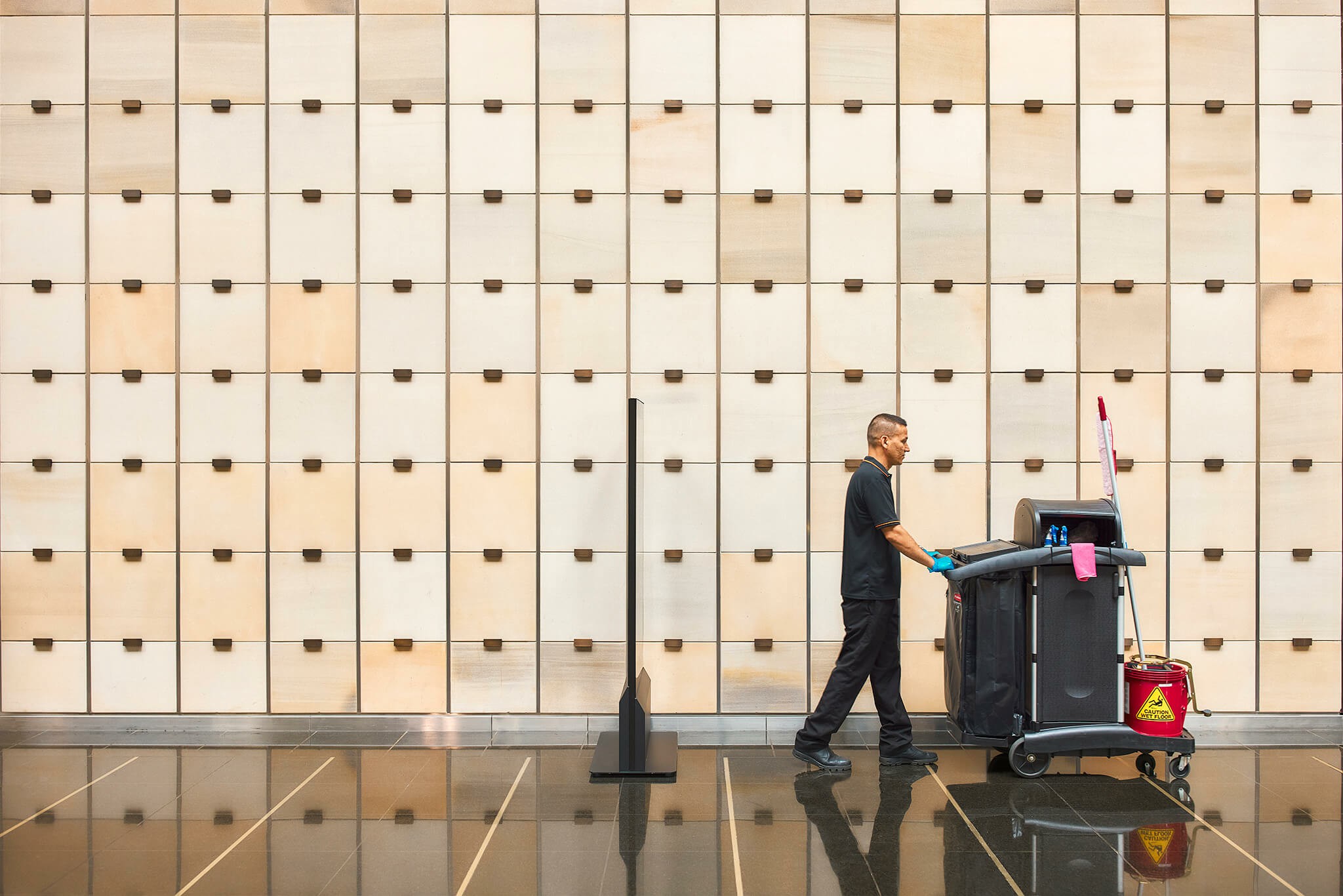 Worker pushing a cleaning cart through an office building